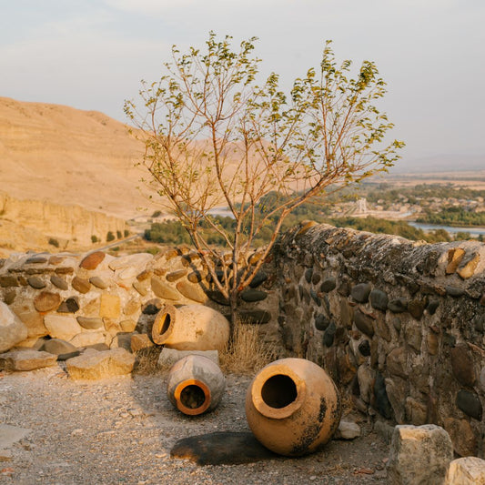 A series of vintage ceramic pots laying on the ground against a stone wall in a mediterranean setting 