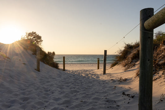 A sun kissed beach in Western Australia with soft sand leading straight out to the sea.